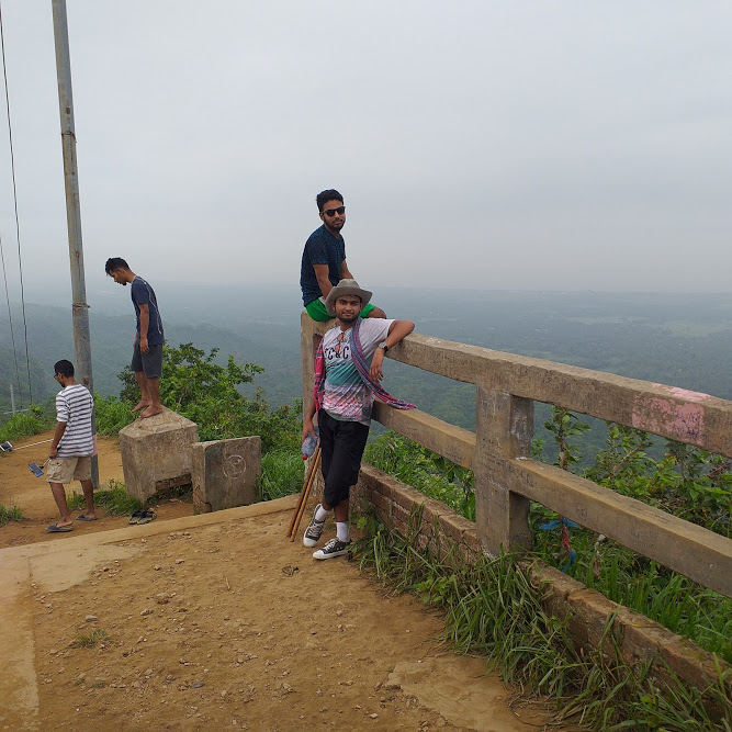 Mahmudul Hasan and Zakir Hossen sitting on a fence at the top of the hill.